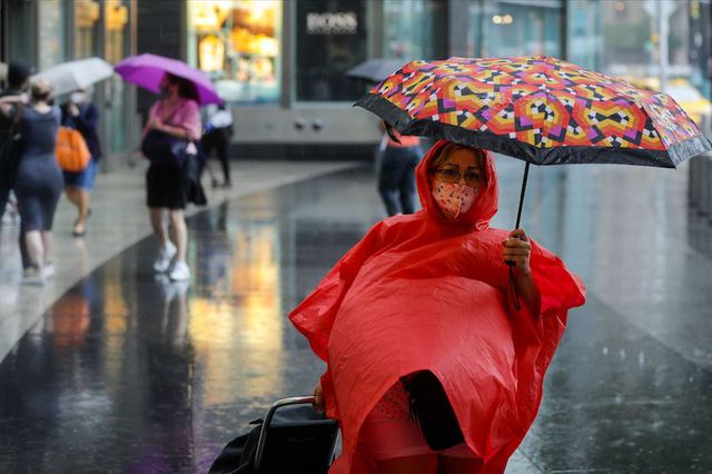A New Yorker holds an umbrella while wearing a poncho and face mask near Columbus Circle as Tropical Storm Fay rained on the city.
